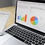 Laptop displaying charts and graphs with tablet calendar for data analysis and planning.